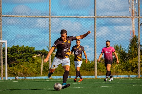 A man kicking a football on a football pitch